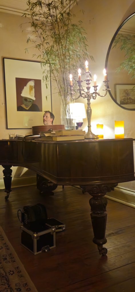 Jon Boden singing at a 19th century piano surrounded by candlelight